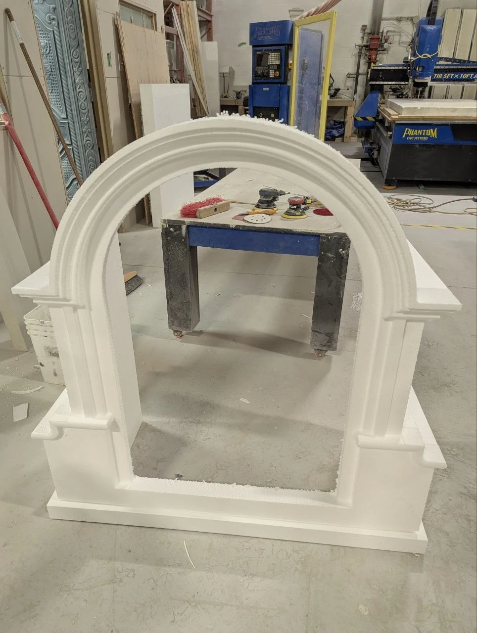 CNC-carved white foam dormer with an arched opening, stepped trim and matching side details in the workshop