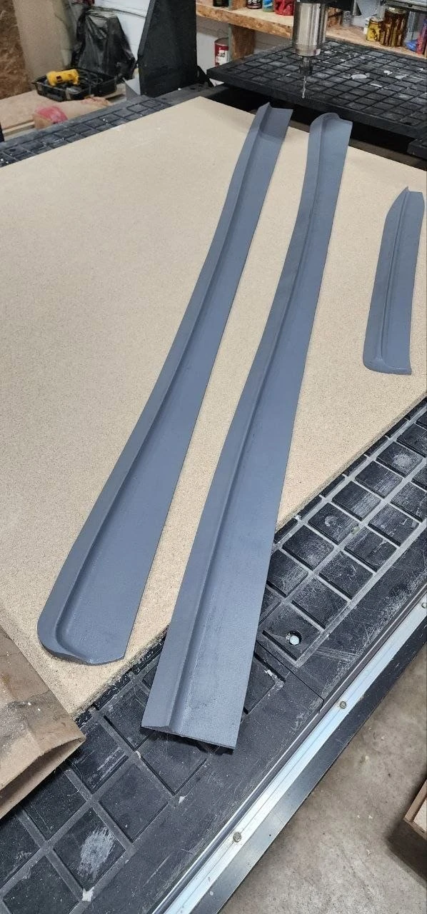Actual grey side-skirt components finished to primer, laid out on the CNC worktable