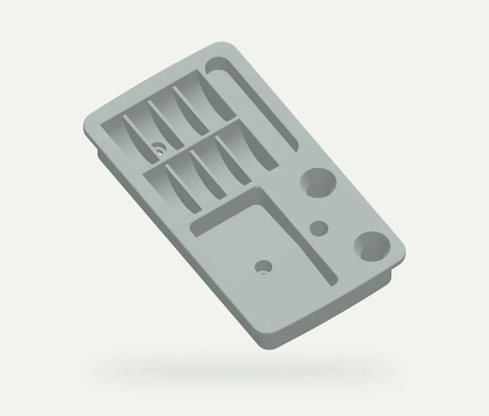 Light grey model render of a rectangular sewing organiser with eight curved slots, round openings and a shallow compartment